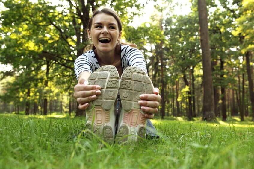 nainen venyttelee nurmikolla