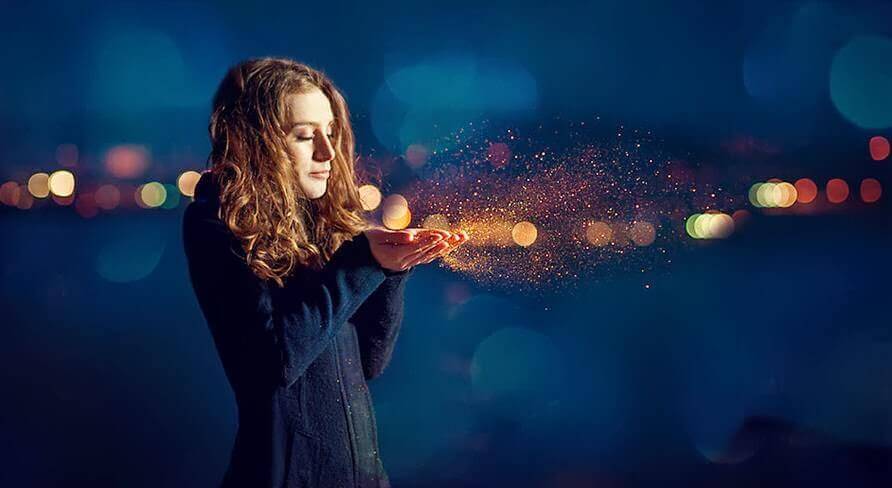 nainen puhaltaa kultapölyä