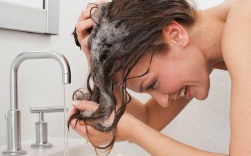 nainen pesee hiuksiaan