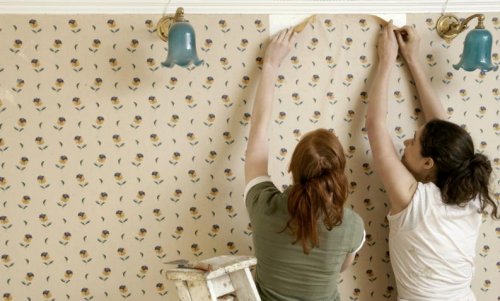 naiset repivät tapettia