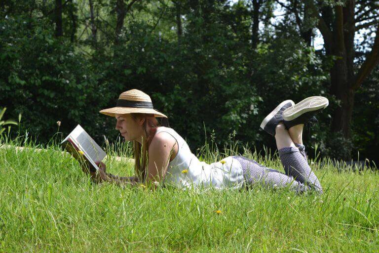 nainen lukee nurmikolla
