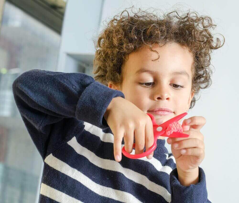 poika leikkaa saksilla