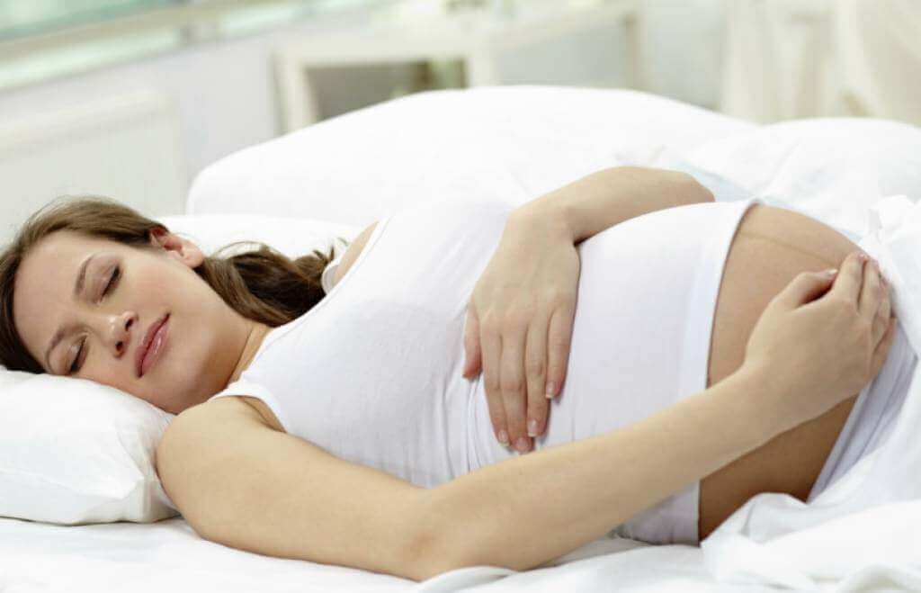 raskaana oleva nainen nukkuu selällään