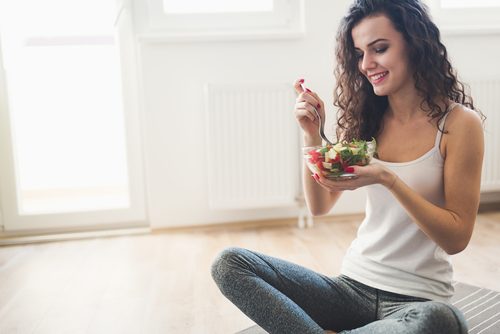 nainen syö salaattia lattialla