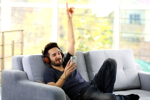 mies kuuntelee musiikkia sohvalla