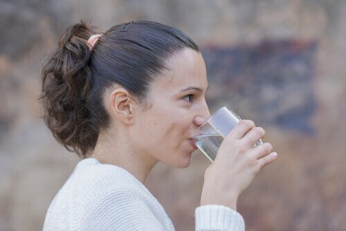 nainen juo vettä hoitaakseen huuliaan