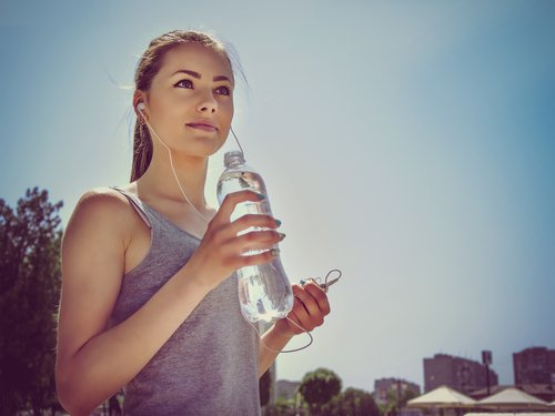 nainen urheilee ja juo vettä
