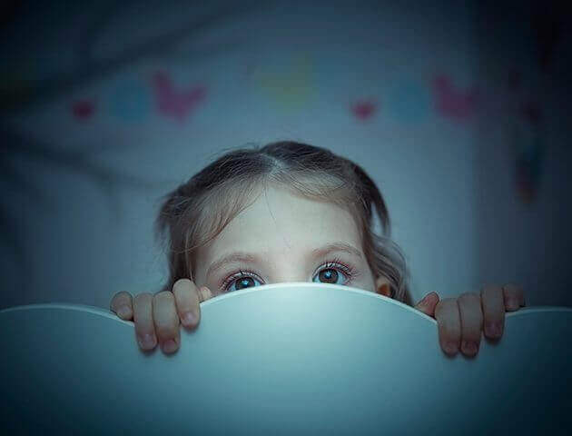 tyttö kurkistaa sängystään