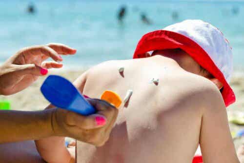 Lasten suojaaminen auringolta aurinkorasvan ja hatun avulla.